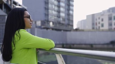 Güneş gözlüklü ve nehir kenarında yürüyen genç bir kadın. Yavaş çekim videosu. İş konsepti