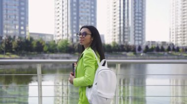 Elinde belgelerle nehrin kenarında yürüyen genç bir kadın. Yavaş çekim videosu