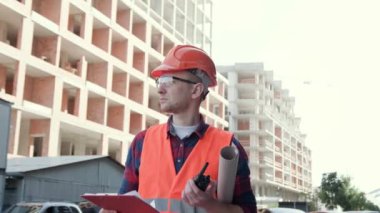 Ustabaşı elinde telsiz ve panoyla sabahleyin tamamlanmamış çok katlı binaları inceliyor. Dolly vurdu.
