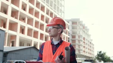 Bitmemiş çok katlı evleri incelemek için elinde broşür ve telsizle neşeli inşaat müfettişi. Dolly vurdu.