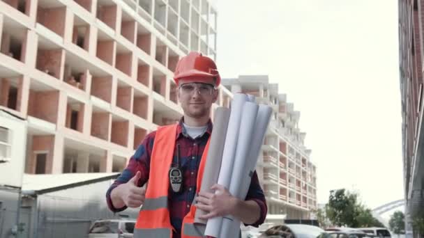 Porträt Eines Lächelnden Bauinspektors Mit Zeichnungen Die Zwischen Unfertigen Gebäuden — Stockvideo