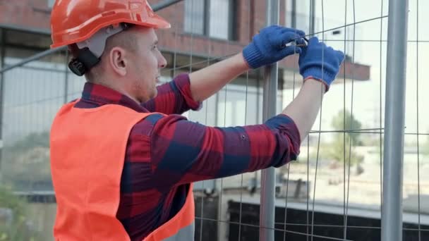Bauarbeiter Arbeitshandschuhen Und Harter Mütze Wickeln Stück Draht Metallzaunpfosten Zeitlupe — Stockvideo