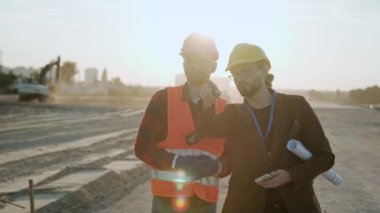 Müdür, koruyucu elbiseli işçiyle konuşuyor, siteye bakıyor. Yavaş çekim videosu