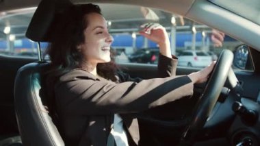 Otoparkta araba süren, müzik dinleyen ve dinlenen mutlu kadın sürücü. Yavaş çekim videosu