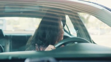 Kapısı açık bir kadın, arabada oturuyor, emniyet kemerini takıyor. Şoför sürmeye hazır. Yavaş çekim videosu