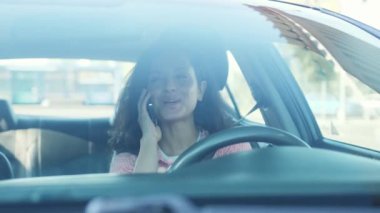 Akıllı telefonu olan bir kadın, park yerinde araba sürüyor ve internetten arıyor. Yavaş çekim videosu