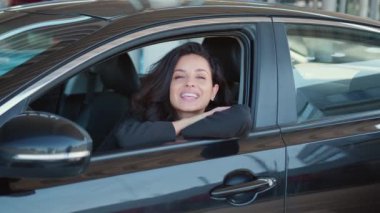 Mutlu genç bayan arabada oturuyor, gülümsüyor ve kameraya bakıyor. Yavaş çekim videosu