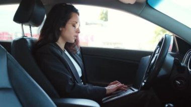 Mutlu kadın portresi açık camlı arabada oturuyor, rahatlıyor, dizüstü bilgisayarda yazıyor. Yavaş çekim videosu