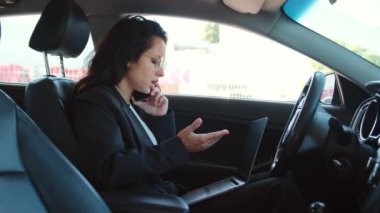 Açık pencereli bir kadın portresi, rahatlıyor, dizüstü bilgisayarda yazıyor ve akıllı telefondan konuşuyor. Yavaş çekim