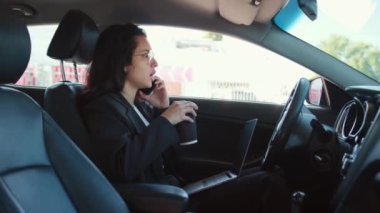 Arabada oturan, kahve içen ve akıllı telefondan konuşan kadın portresi. Yavaş çekim videosu