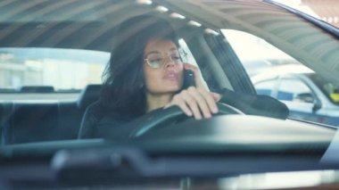 Gülümseyen kadın sürücü elinde cep telefonu, arıyor, arabada oturuyor. Yavaş çekim videosu