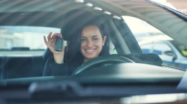 Gülümseyen bayan arabada oturuyor, anahtarları gösteriyor. Araba satın alma kavramı. Yavaş çekim videosu