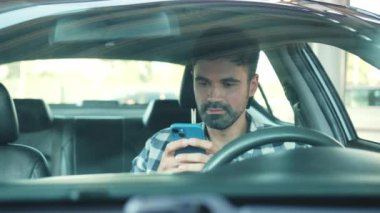 Arabada otururken gülümseyen erkek sürücü cep telefonu kullanıyor. Ulaşım, teknoloji, yaşam tarzı konsepti. Yavaş çekim