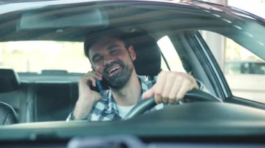 Akıllı telefonda konuşurken arabada oturan gülümseyen adam. Ulaşım, teknoloji, yaşam tarzı konsepti. Yavaş çekim