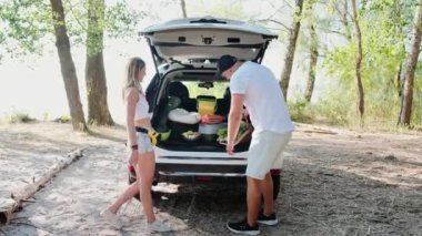 Piknik için sepet dolusu yemek tutan mutlu bir adam, ormanda bir kadını öpen. Hafta sonu, seyahat, aktif tatil konsepti. Yavaş çekim