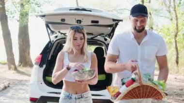 Güzel bir kadın kasede elma taşırken bir adam bir sepet erzağı tutuyordu. Hafta sonu, seyahat, aktif tatil konsepti. Yavaş çekim