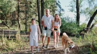 Mutlu bir aile ve köpek ormanda yürürken birlikte hafta sonu geçiriyorlar. Aile, yaz tatili konsepti. Yavaş çekim