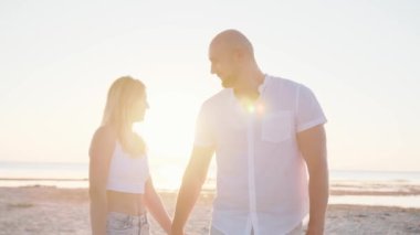 Mutlu çift el ele tutuşuyor, yürüyor, deniz kıyısında dans ediyor. Romantik, ilişki konsepti. Yavaş çekim