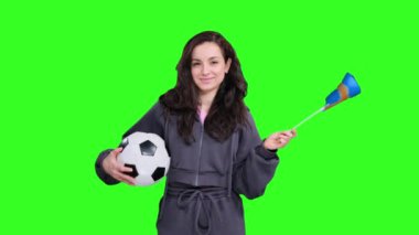 Yeşil izole edilmiş bir yerde elinde futbol topu tutarken İsveç bayraklarıyla poz veren ve dalgalanan mutlu genç bayan hayranlar.