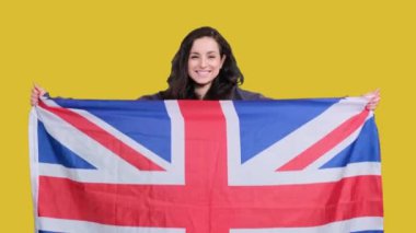 Sarı izole edilmiş İngiliz bayrağını gururla tutan gülümseyen genç bayan. Destek, ulusal kimlik