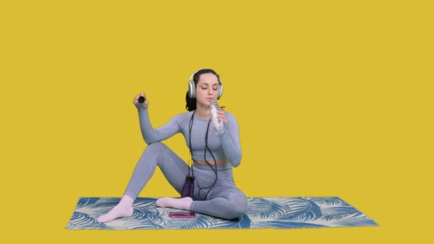 Jonge Vrouw Hoofdtelefoon Met Springtouw Zittend Yogamat Terwijl Rust Training — Stockvideo