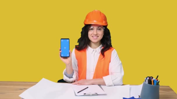Glimlachende Jonge Vrouwelijke Ingenieur Beschermende Helm Tonen Telefoon Scherm Gebaar — Stockvideo