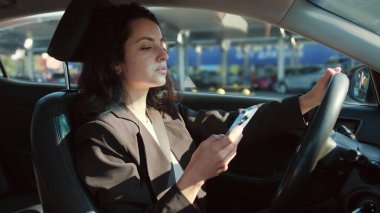 Akıllı telefon tutan gülümseyen kadın, park yerinde araba süren ve sohbet eden. Yavaş çekim videosu