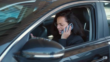 Gözlüklü kadın portresi açık camlı arabada oturuyor, telefonu tutuyor ve duygusal olarak konuşuyor. Yavaş çekim videosu