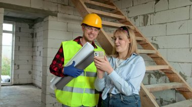 Female engineer and foreman using smartphone during inspection of unfinished residential house. Slow motion clipart