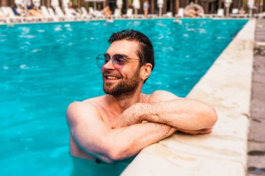 Güneş gözlüklü mutlu sakallı adam açık havuzda tatilinin tadını çıkarıyor. Uzayı kopyala Yaz zamanı, tatiller, yaşam tarzı konsepti