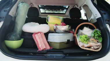 Bir arabanın bagajına koyulan piknik için taze yiyecek, ekipman, yakacak odun. Hafta sonu, seyahat, aktif tatil konsepti. Yavaş çekim