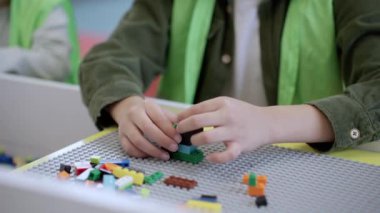 Oyun merkezindeki masada oyuncak renkli bloklar kullanırken, güvenli yelek binasındaki Afrikalı Amerikalı küçük çocuk. Seçici odaklanma. Yavaş çekim çocukluk, eğlence, meslek konsepti