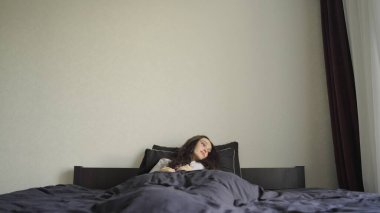 Genç bayan yatak odasında uyanırken esniyor ve esniyor. Ağır çekim. Yaşam tarzı kavramı