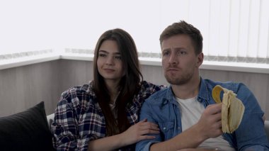 Karantina sırasında mutfakta genç bir çift. Kanepede birlikte oturup televizyon ya da film izleriz. Adam muz yiyor. Etrafı çöpleri geri dönüşümle çevrili. Kamera geri gidiyor