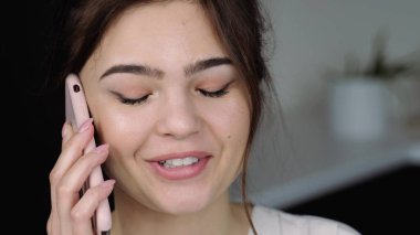 Karantina sırasında mutfakta genç bir kadın. Akıllı telefondan konuşuyor. Evden çalışan bir kadının portresi.