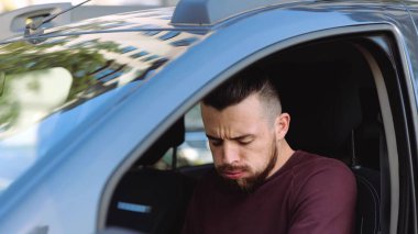 Arabanın içindeki genç adam. Elinde kötü bir uyarı olan adamın yan görüntüsü. Bir tane de göğsünde tut. Acı verici bir doğum. Arabada hasta biri var.