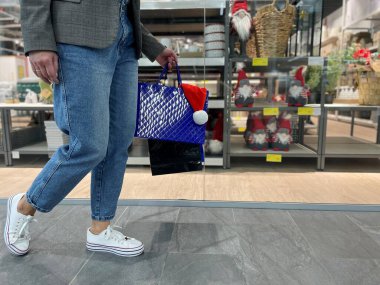 Şehir merkezindeki alışveriş merkezinde elinde hediyelerle gezen bir kadın. Bayram indirimi sırasında alışveriş merkezindeki kadınların bacaklarını kapatın. Satışlar, satın alma kavramı