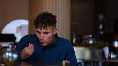 Close up of Caucasian handsome man having lunch or supper eating in restaurant alone. Young businessman eats tasty meal. Diet. Nutrition. Healthy food concept. Slow motion. Healthy lifestyle