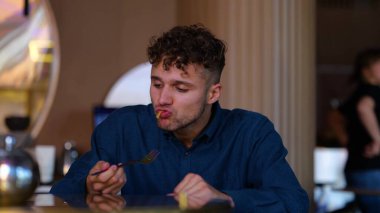 Happy young man sitting in cafe indoor and eating wok food. Close up of handsome Caucasian guy in modern restaurant having tasty meal. Delicious food. Healthy lifestyle. Spicy flavour