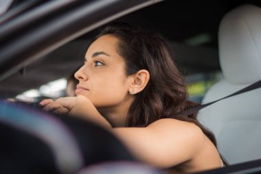Genç ve güzel bir kadın sürücü yolculuk sırasında dinleniyor ve direksiyona yaslanıyor. Yolculuk, seyahat, yaşam tarzı, ulaşım konsepti