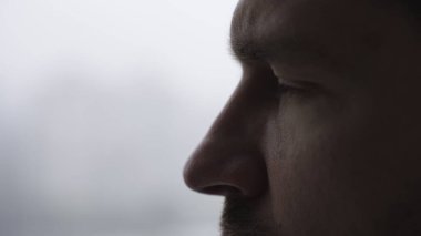 Beyaz arka planda izole edilmiş beyaz bir genç adam. Yan görüş, yakın çekim, kopyalama alanı. Ağır çekim. Duygular konsepti