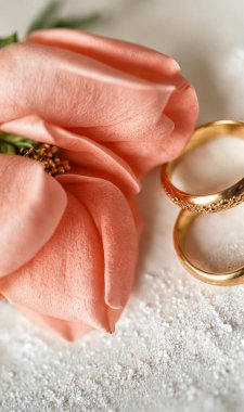 Düğün konsepti. Beyaz desenli arka planda bir alyans ve çiçek.