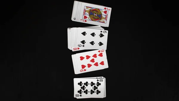 Several playing cards deck, entertainment with cards, lined up, isolated on black background, top view