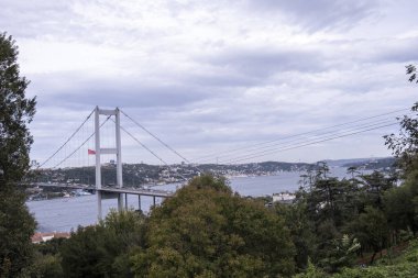 İstanbul Boğazı ve Nakkastepe Milli Bahçesi 'nden geniş açılı manzara, ağaçlar ve bulutlu hava, İstanbul turizm afişi, 15 Temmuz Şehitler Köprüsü, ulaşım fikri