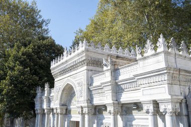 Pertevniyal Valide Sultan Camii 'nin dışı, ağaçlı cami girişi, detaylı tarihi eserler, mavi gökyüzü, İstanbul eski camisi.