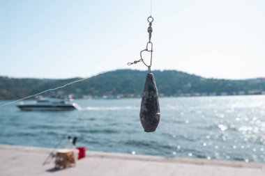 Fishing lead with blurred Bosphorus, wide angle fishing equipment, angling in Istanbul, angling concept banner clipart