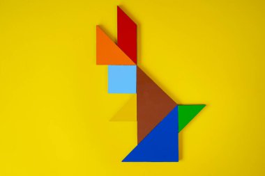Tangram tavşanı, tangram hayvan tavşanı, uzanmış, sarı arka planda izole edilmiş, renkli tangram tavşanı, yapboz oyuncağı konsepti