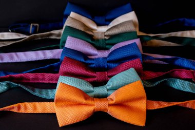 Peş peşe dizilmiş renkli papyonlar, erkek kıyafetleri aksesuar moda konsepti, önde turuncu kravat, seçici odaklanma