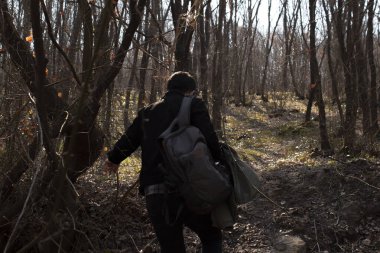 Ormanda çamurlu ve engebeli bir yolda yürüyen bir adam, doğada çamurlu ve kayalık bir yol, sırt çantasıyla dolaşan genç bir adam.
