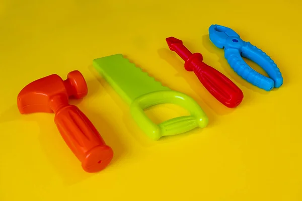 黄色背景的彩色修补玩具 黄色背景的儿童游戏 游戏理念 彩色螺丝刀锯锤 顶视图 — 图库照片